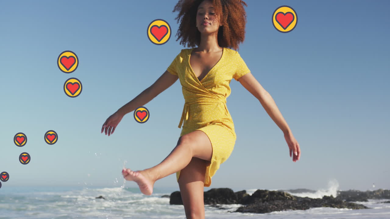 animación de iconos digitales de corazón sobre una mujer bailando en la playa
