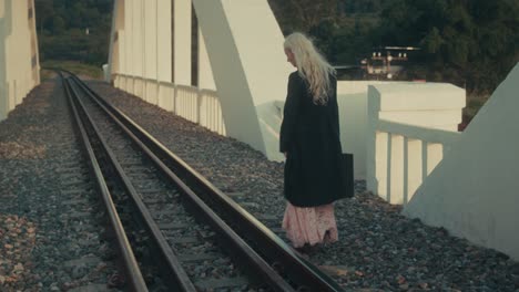 woman walking on train tracks bridge