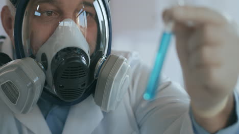 a male professor examines a test tube with a blue solution with a virus covid. high quality 4k footage