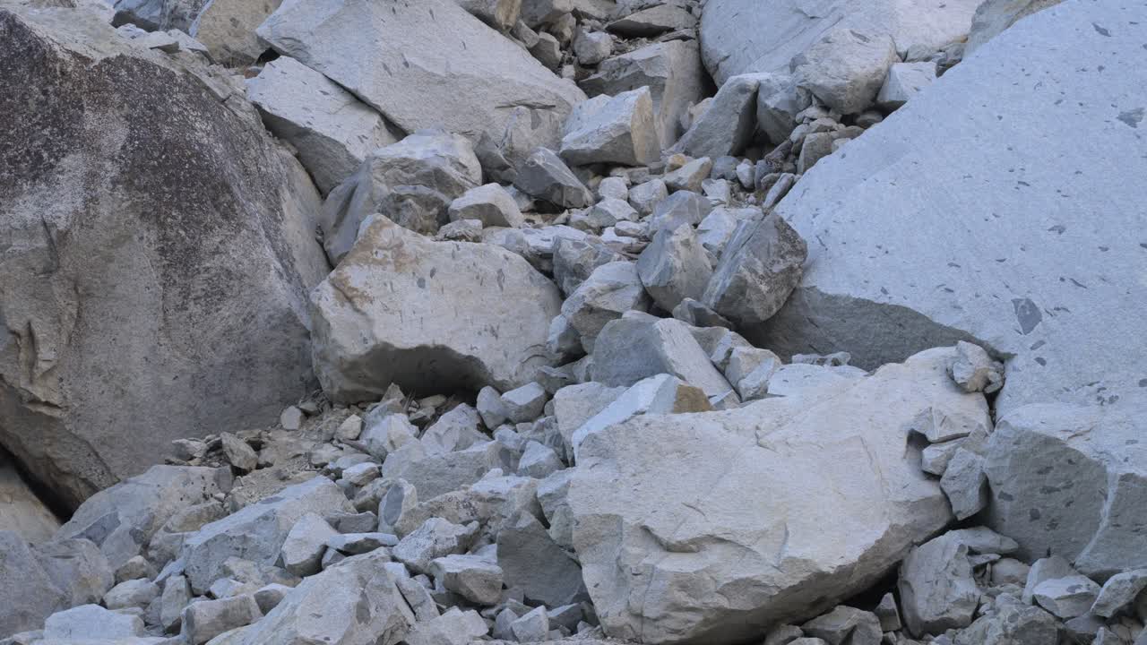 Footage featuring a tilt-down shot of giant granite boulders nestled within the rugged terrain of Yosemite National Park, California.