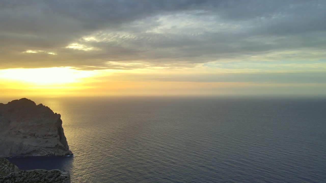 Experience a breathtaking sunset over the tranquil Mediterranean Sea near Pollensa, Mallorca. The vibrant colors and serene water create a peaceful atmosphere, ideal for relaxation.