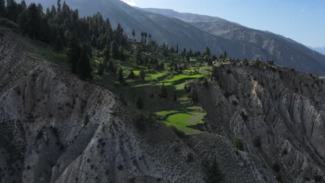 Luftaufnahme-Eines-Dorfes-Im-Hochland-Pakistans,-Siedlung-Auf-Einer-Klippe-Und-Grüne-Wiesen,-Drohnenaufnahme