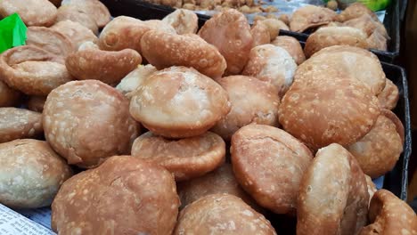 Closeup-of-Indian-street-food-Samosa,-Kachori,-and-pakora-on-a-cart-in-a-busy-market-area