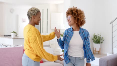 una pareja de lesbianas felices y diversas bailando en la sala de estar a cámara lenta.