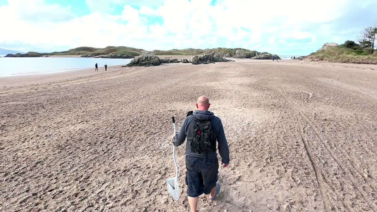 Following healthy active male walking dog on beautiful sandy Welsh beach for early morning exercise