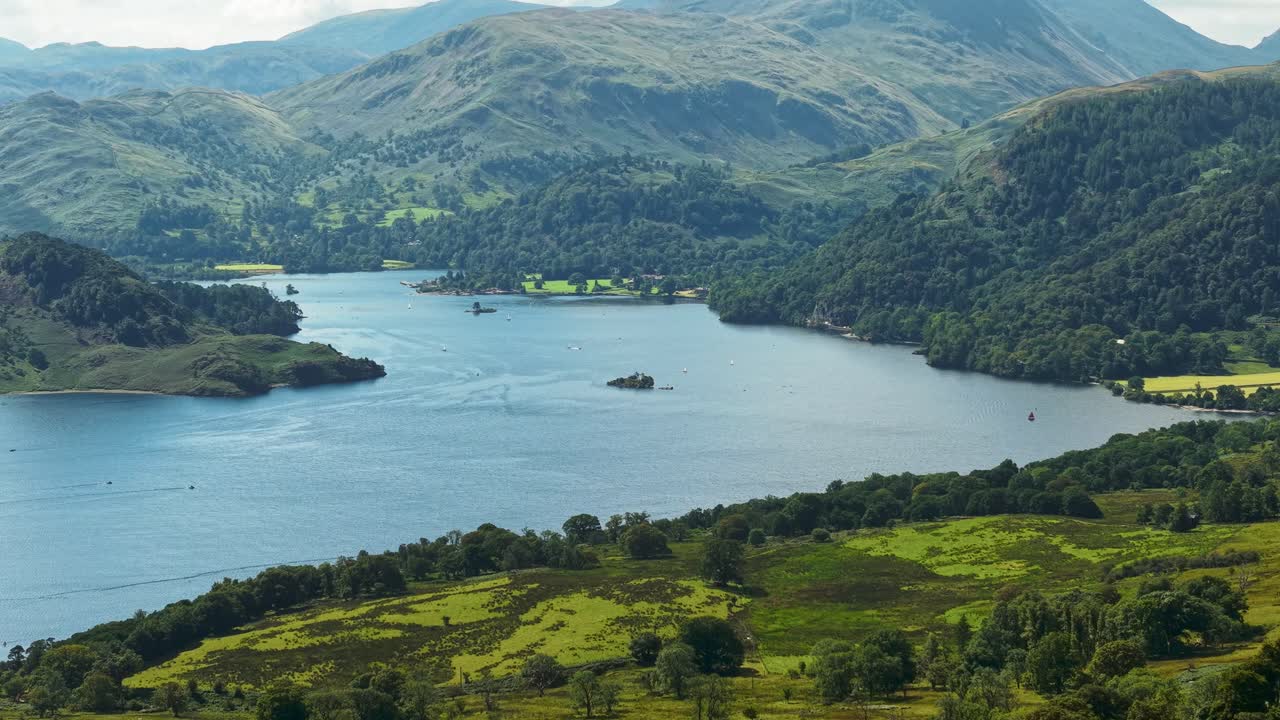 Sideways panning drone view of Ullswater lake, islands and fells in summer
