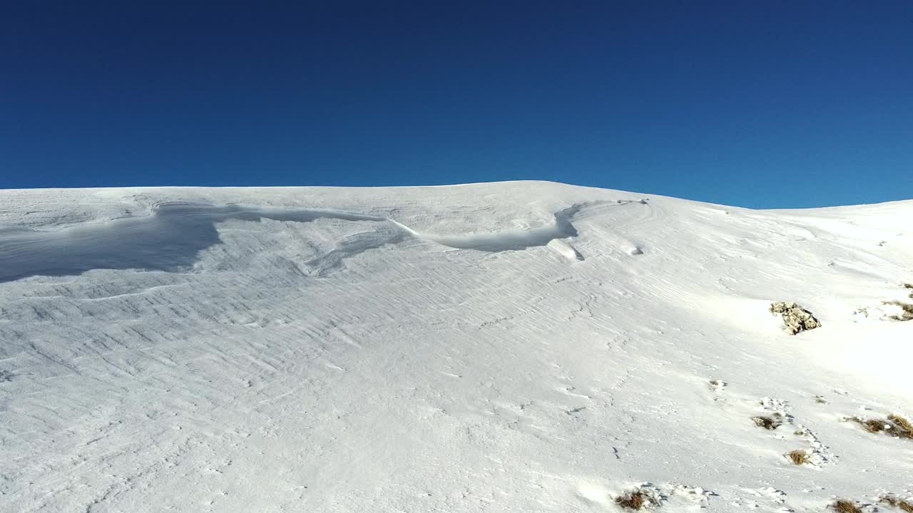 snow on top of a mountain on a sunny day, aerial shot