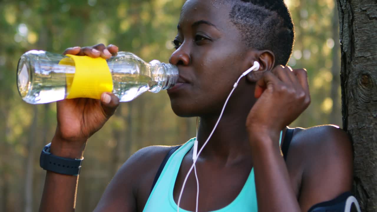 una corredora bebiendo agua en el bosque 4k