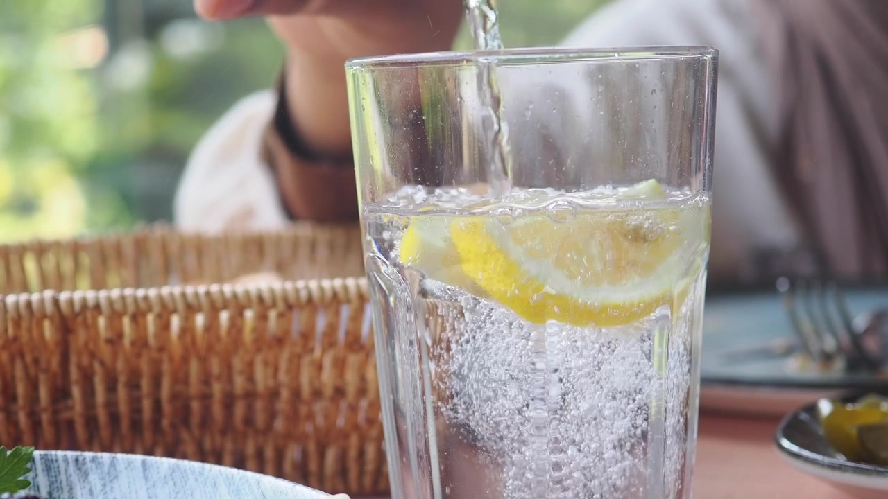 Pouring Sparkling Water into a Glass with Lemon Slices