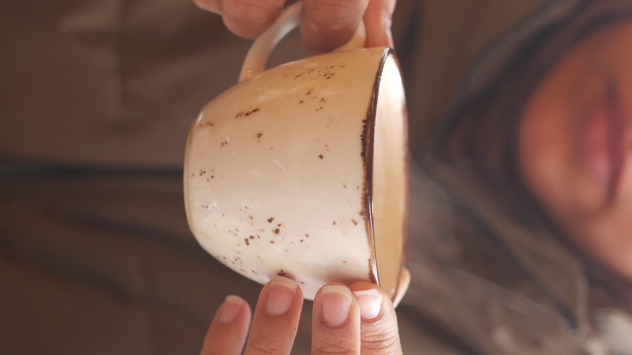 mujer sosteniendo una taza de bebida caliente