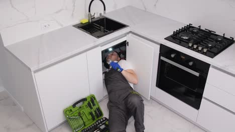 a plumber in protective work clothes and gloves is doing plumbing work a plumber in protective work clothes and gloves is doing plumbing work replacing an old broken sink filter plumbing services