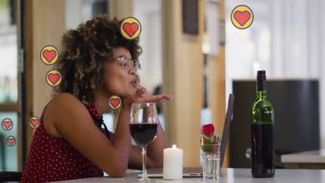 Animation-of-hearts-over-african-american-woman-drinking-wine-and-having-video-call
