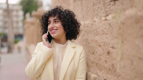 young woman smiling confident talking on the smartphone at street