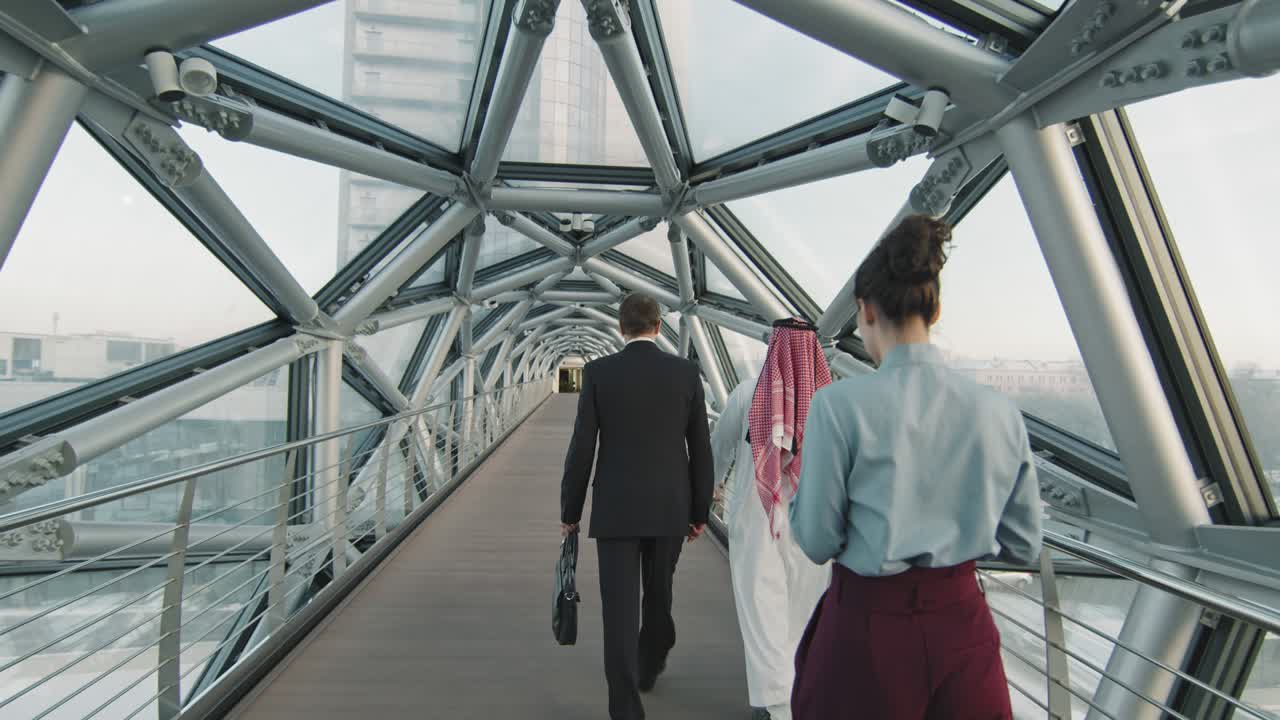 personas de negocios que van a trabajar a lo largo de un puente de vidrio cubierto