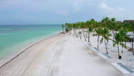 paradise scenic summertime flight above empty, desolate and deserted juanillo white powder beach resort by turquoise sandy beach, cap cana, dominican republic, covid-19 pandemic, aerial approach