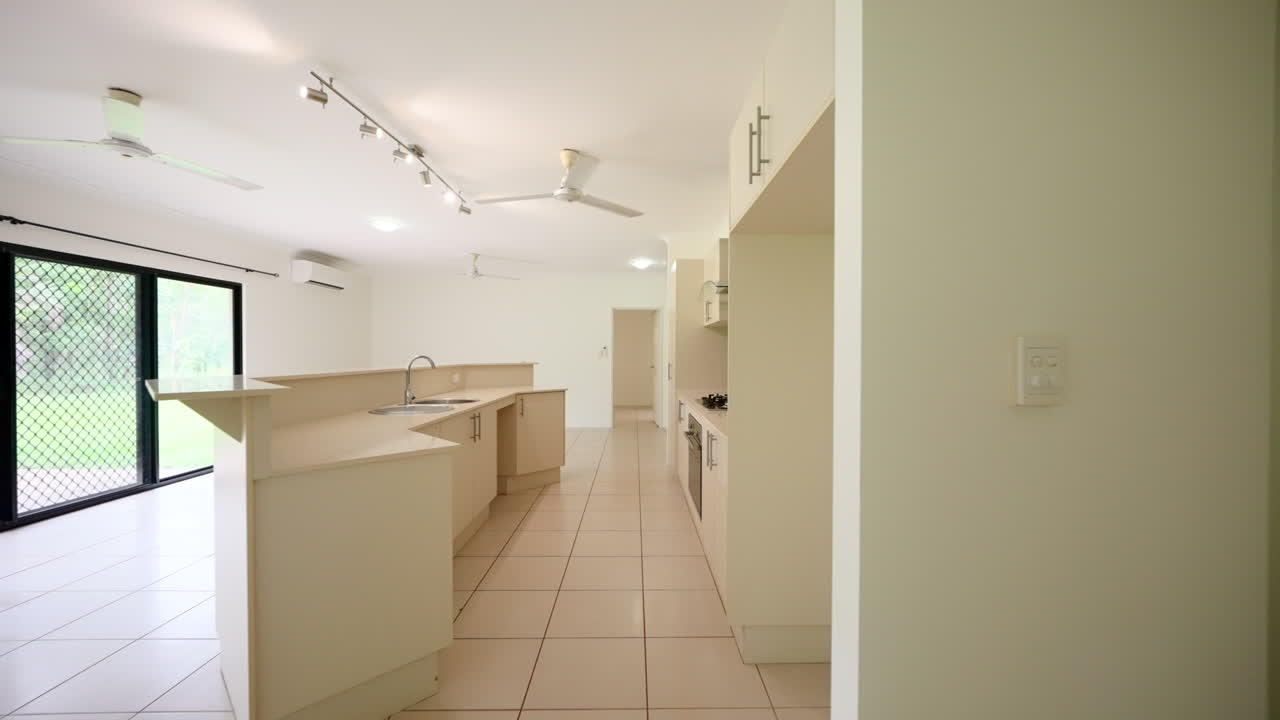 vacante gran cocina beige moderna y mostradores claros a un gran dormitorio vacío con puertas deslizantes de gabinete de espejo