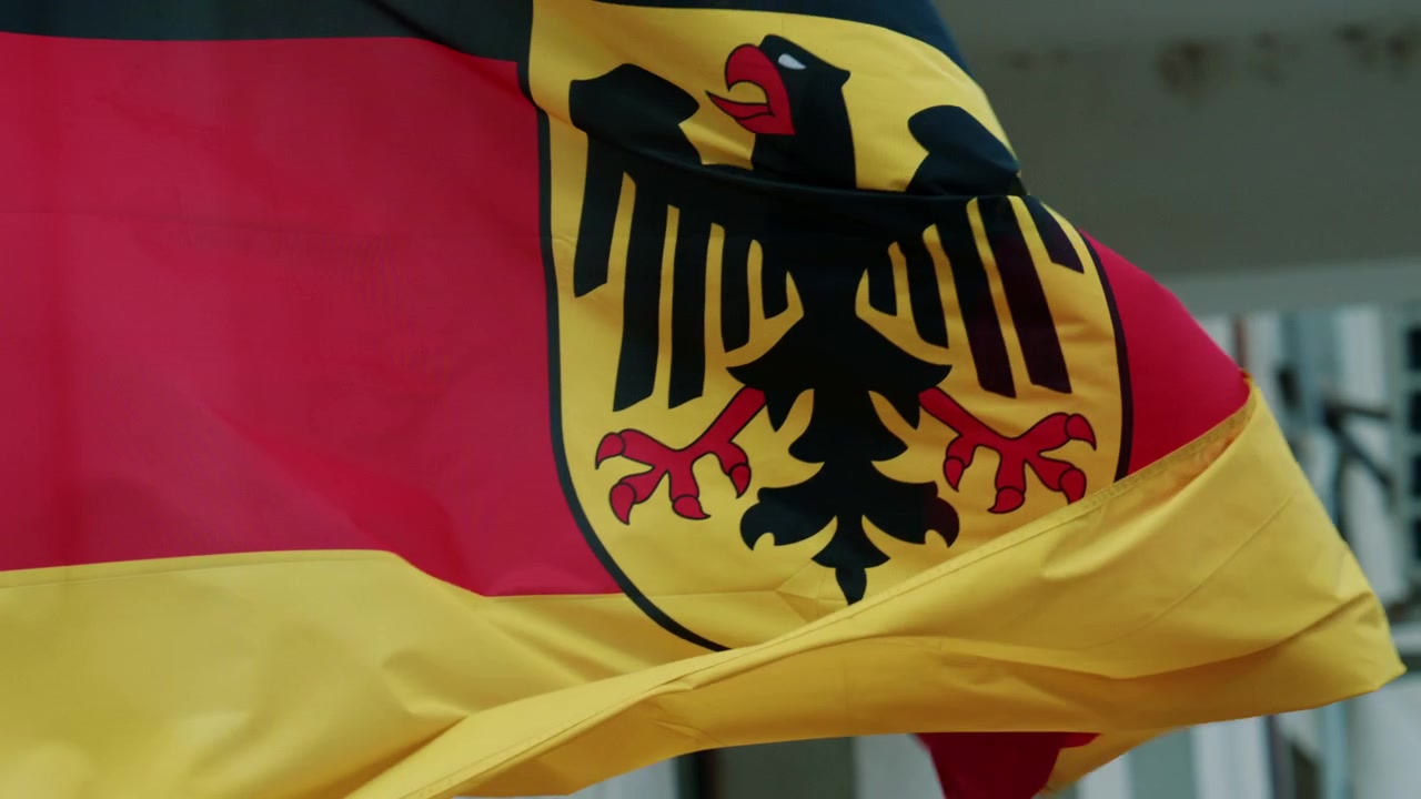 Bandiera nazionale tedesca che sventola al vento, mostrando i colori nero, rosso e oro con l'emblema dell'aquila.