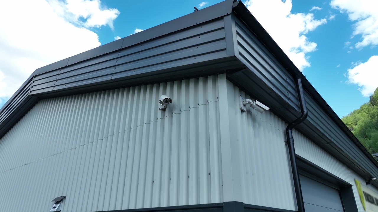 Ripresa in movimento dal basso di due telecamere di sorveglianza montate su un edificio, che enfatizza la sicurezza e la sorveglianza