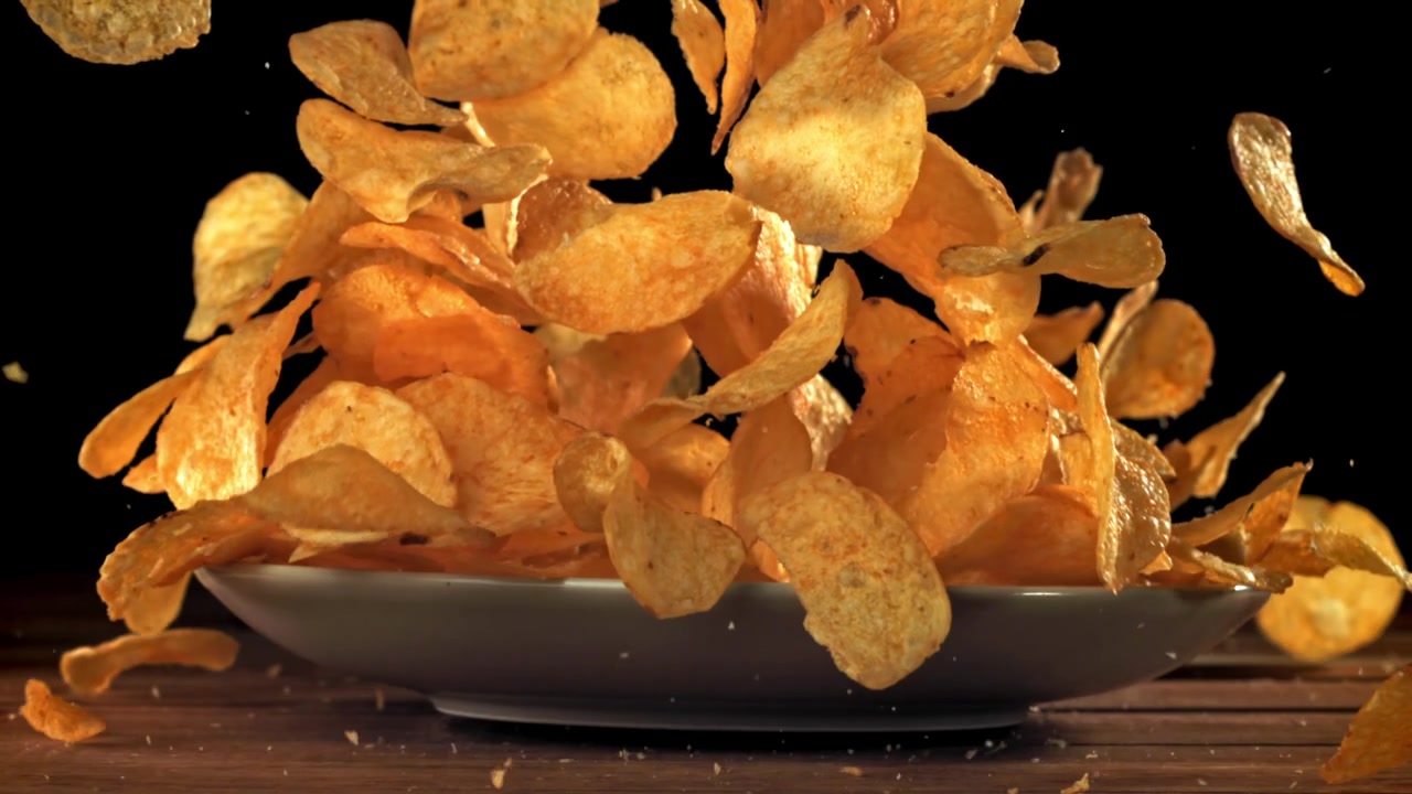 Crispy Potato Chips Bursting from a Plate in Slow Motion