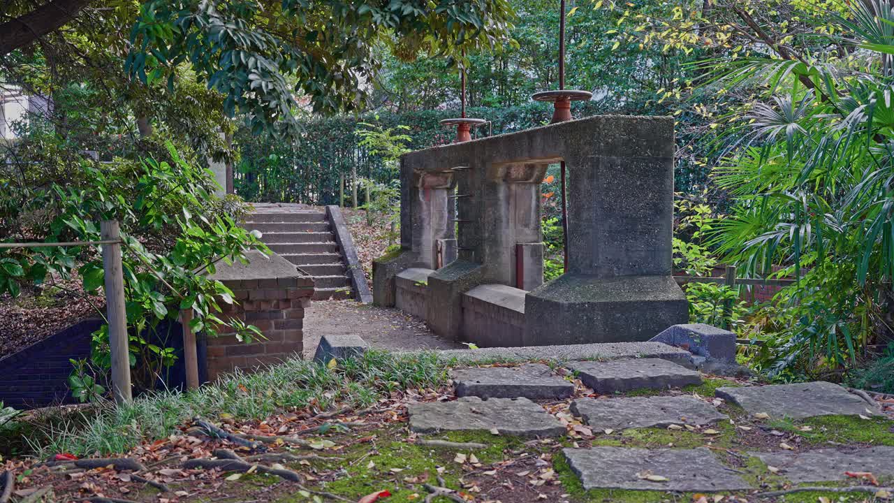 A view of the historic stone gate structure of the Jinzaemon Weir, surrounded by dense greenery and stone steps