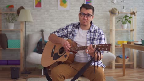 joven músico con gafas no puede tocar la guitarra