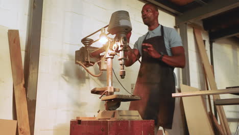by lamp switching on african american male crew inspecting drill press and giving warnings in shop