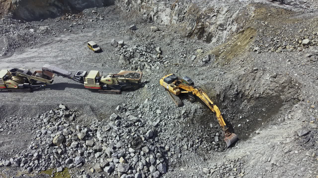 Granite quarry operation with heavy machinery in active site near rocky terrain during daytime