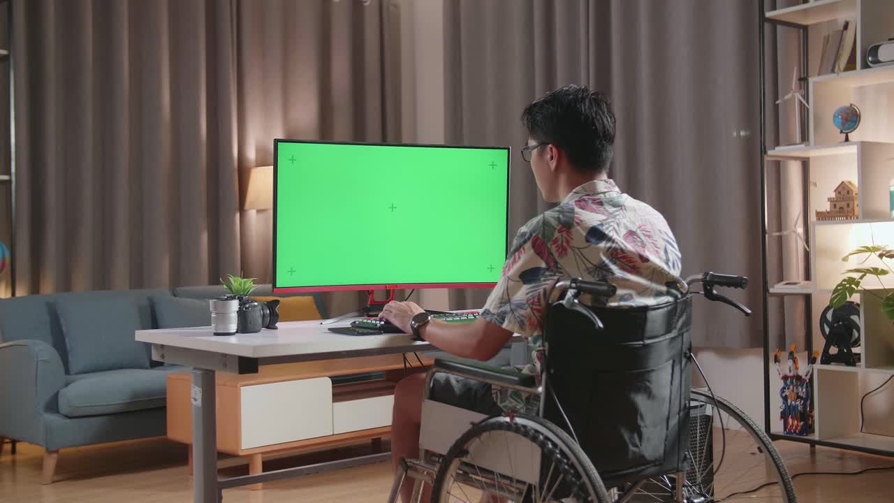 체어 에 앉아 있는 사람 이 초록색 화면 을 가진 컴퓨터 에서 일 하고 있다