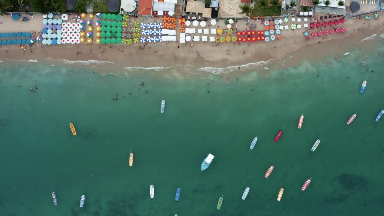 브라질 페르남부쿠(pernambuco)의 유명한 포르토 데 갈린하스(porto de galinhas) 또는 치킨 포트 해변(chicken port beach)의 조감도 하향식 공중 이동 샷, 브라질 호텔, 화려한 우산, 천연 수영장과 범선에서 수영하는 관광객