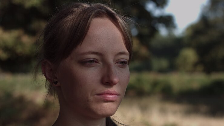 A young woman is seen in a close up while facing the side and having the sun's rays fall on her face