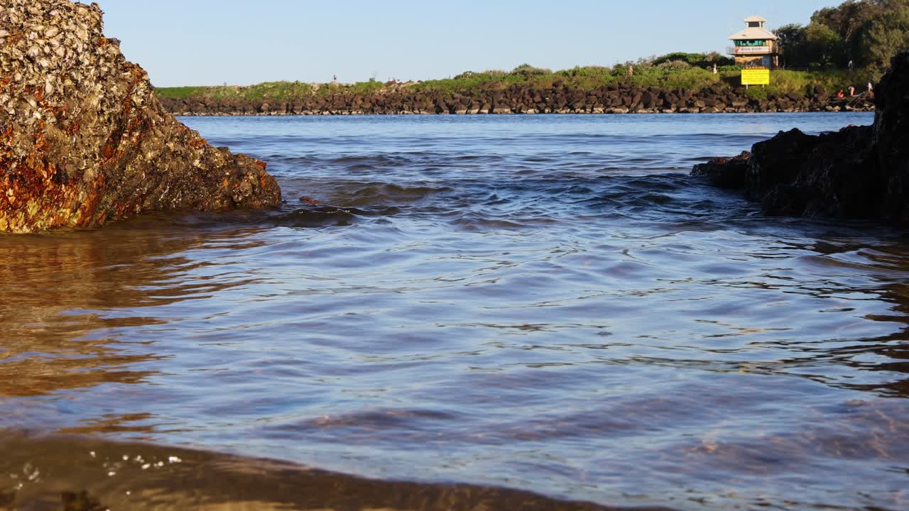 las olas chocan suavemente contra la orilla rocosa