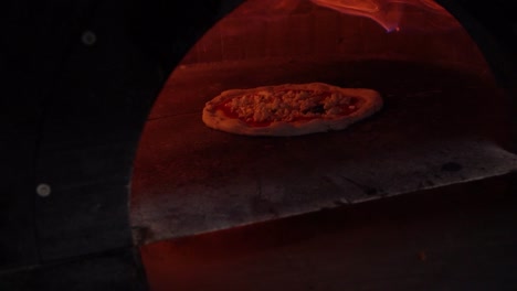 pizza baking in an italian pizza oven with fire around it in slow motion