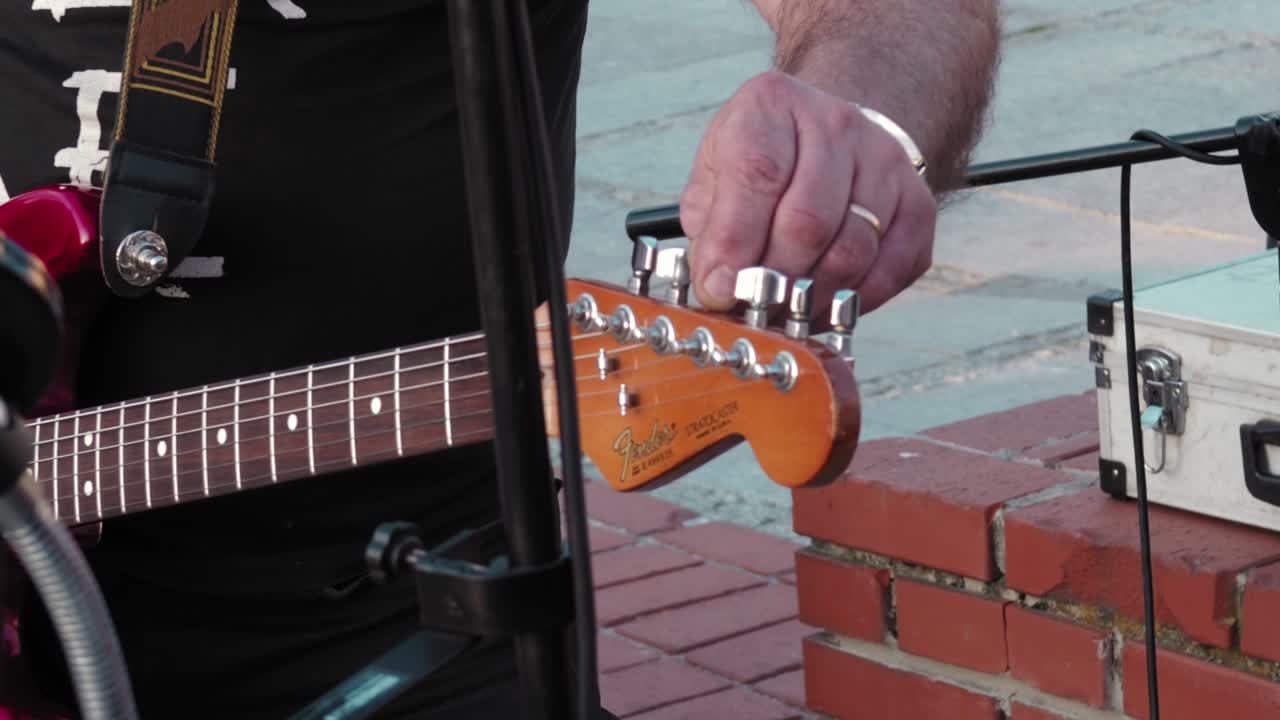 Man, musician is tuning the guitar. Preparing for street performance.