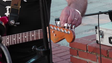 man, musician is tuning the guitar. preparing for street performance.