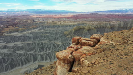 aerial view of man standing on top of the cliff above abyss and desert landscape of utah usa, orbit drone shot