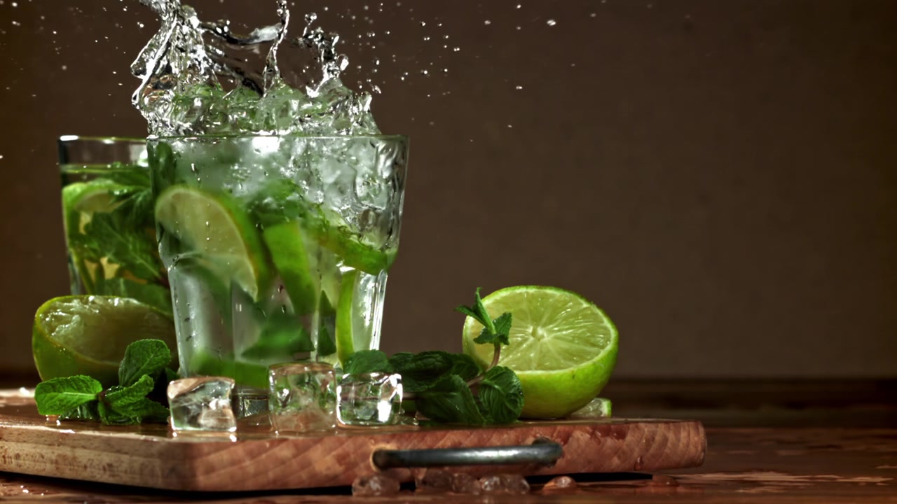Gerak Lambat Es Batu Terciprat ke dalam Minuman Mojito yang Menyegarkan