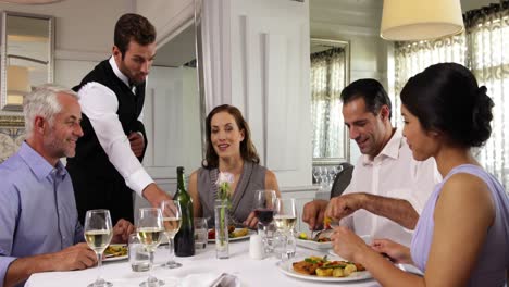 camarero asistiendo a una mesa de amigos felices