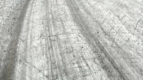 Tilt-Up-Aerial-View-of-Frozen-Ice-in-Valley-Under-Aletsch-Glacier,-Swiss-Alps,-Switzerland