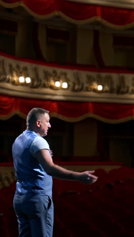 rehearsal before the performance. actor man is talking to the empty auditorium during pandemic in the world. speaker talking in the theater with no people. vertical video