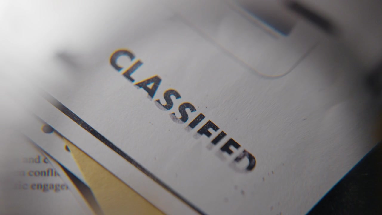 Primo piano su una lente d'ingrandimento che ingrandisce un timbro di gomma su un documento classificato, un fascicolo dall'aspetto top secret governativo con informazioni di intelligence riservate, nascoste o rivelate da un informatore o un detective.