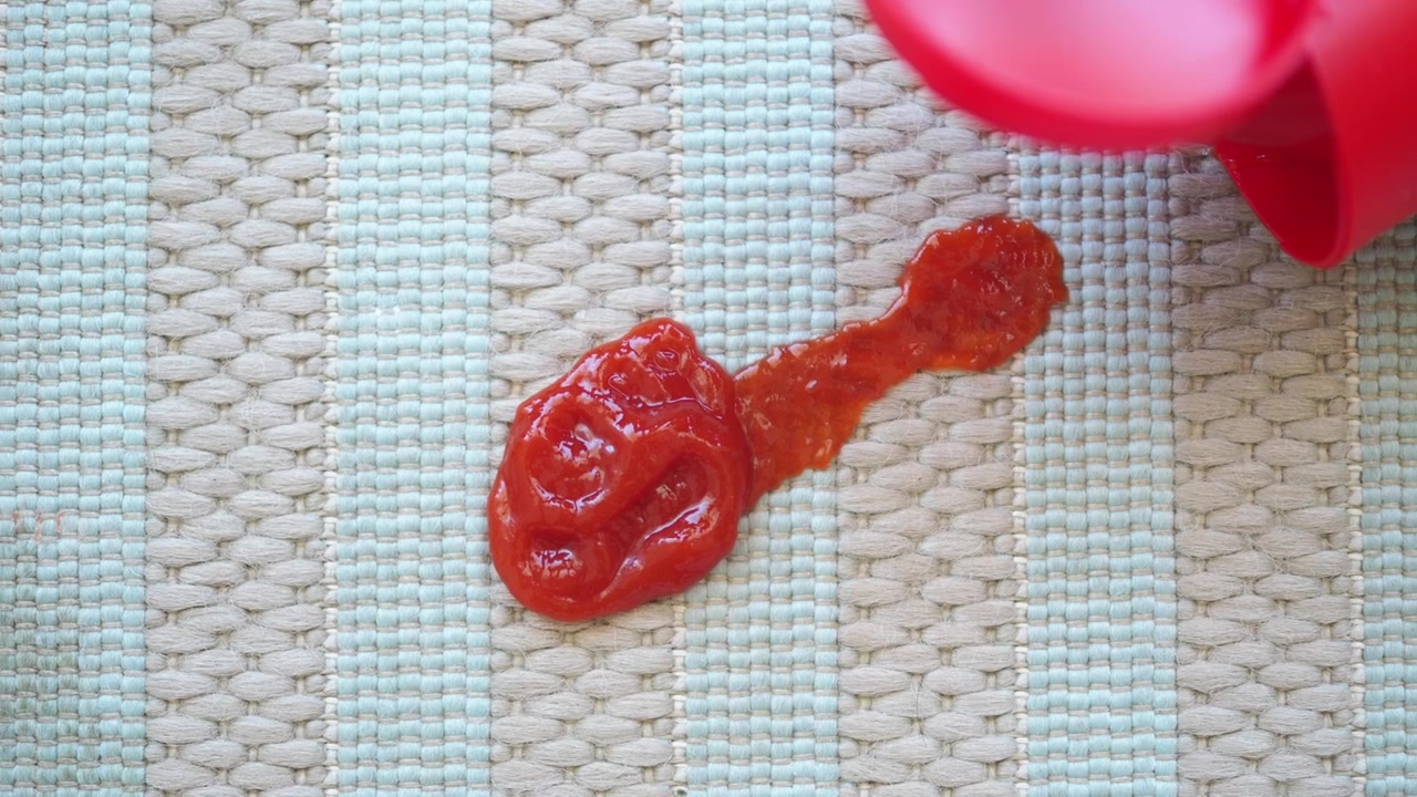 Nahaufnahme von verschüttetem Ketchup auf einem gestreiften Platzset