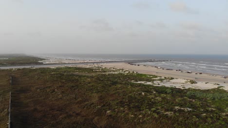 Fast-180-degree-scenic-pan-left-of-the-ocean,-dunes,-grass-lands,-jetty