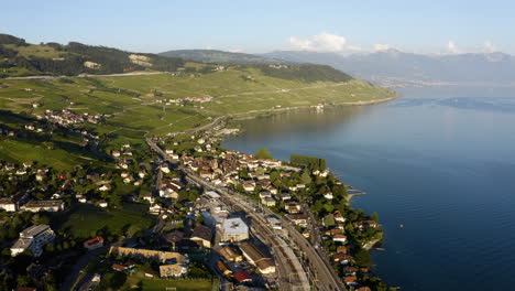 aerial view of vineyards, cully village, and railroad on lakefront of lake geneva in lavaux, switzerland