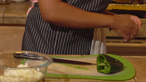 mujer negra quita el núcleo de pimiento jalapeño y las rebanadas en la cocina, primer plano