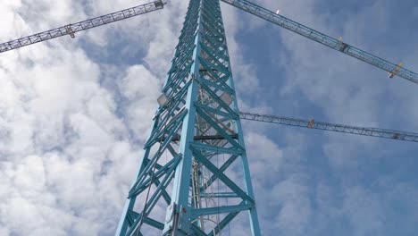 Columna-Metálica-De-Grúa-De-Construcción-Con-Escaleras-Y-Cielo-Azul-Nublado-En-El-Fondo