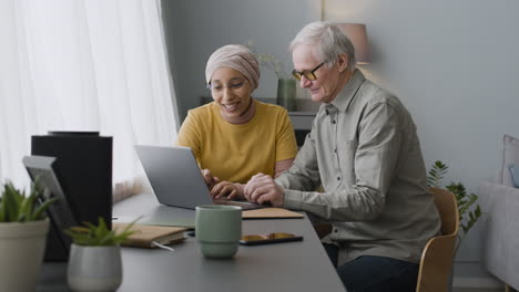 arabic woman teaching an elderly man to use a laptop 3