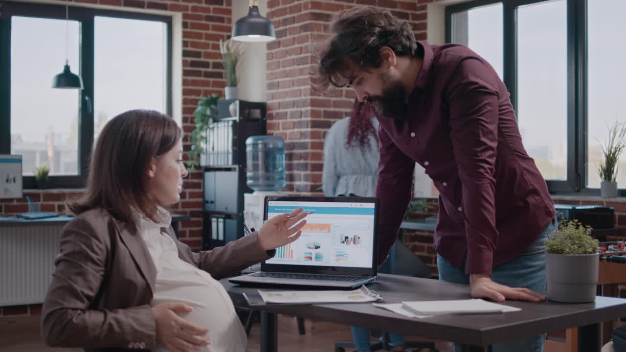 Business woman expecting child, working on analysis with colleague
