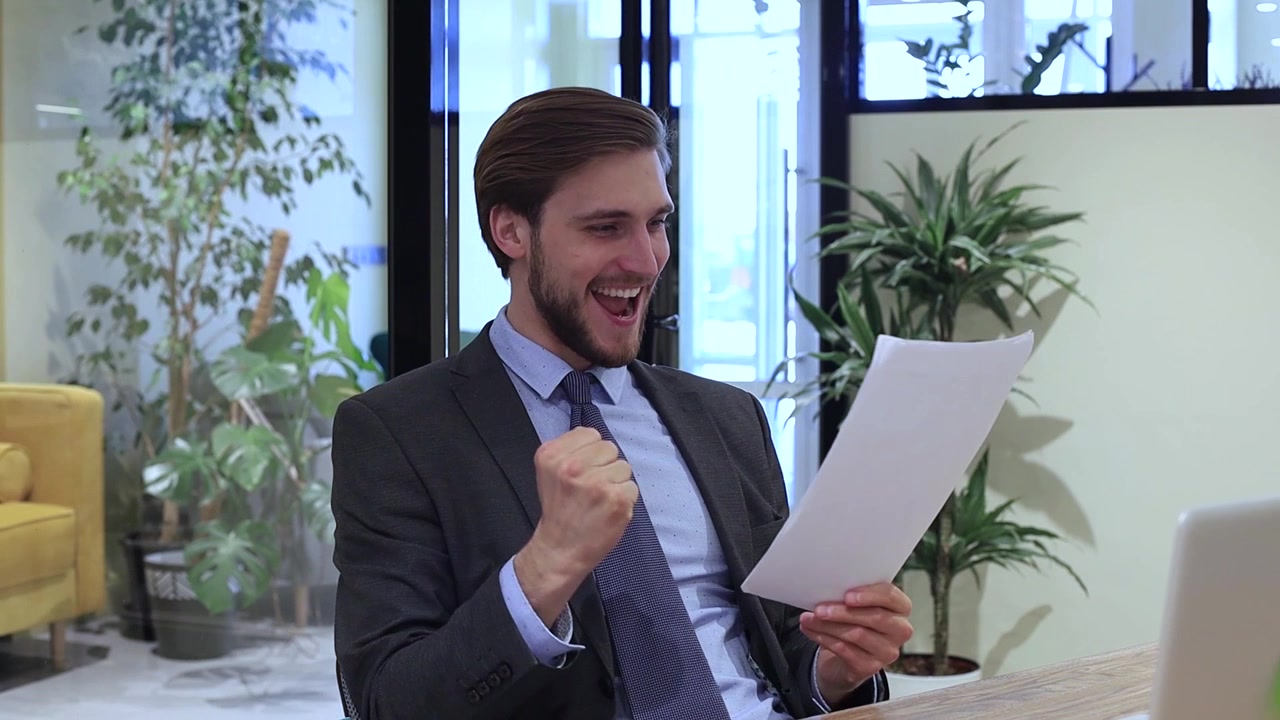 Uomo d'affari felice che celebra il successo con documenti in un ufficio moderno