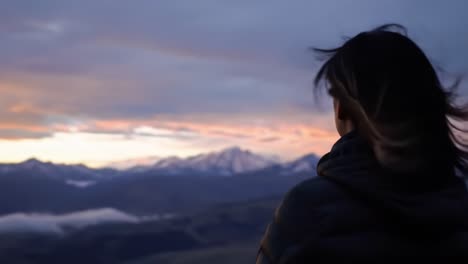 contemplative woman overlooking majestic landscape as sunset paints the sky with vibrant colors in a serene natural setting