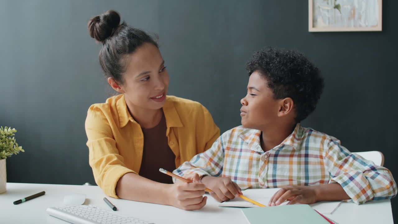 African Boy Doing Homework at Home with Help of Mother